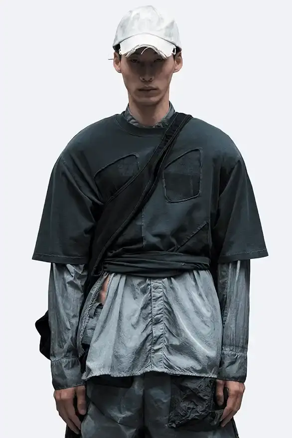 RADIO ECHOES: A-COLD-WALL* TUNES INTO UK ROOTS FOR SS25 pic of A-COLD-WALL*'s Spring/Summer 2025 collection called "Pink Noise," which draws inspiration from British radio culture. The piece describes the collection's technical outerwear, including utility jackets with toggles and drawstrings, ice blue collared jackets paired with loose shirts, color-blocked knitwear in black, brown and cream, graphic t-shirts, ribbed vests, and practical sling bags. The article notes that this collection follows the departure of founder Samuel Ross and the brand's acquisition by Four Marketing. The collection maintains A-COLD-WALL*'s signature gorpcore aesthetic with functional designs and is currently available on the brand's website. (image 5 of 9)