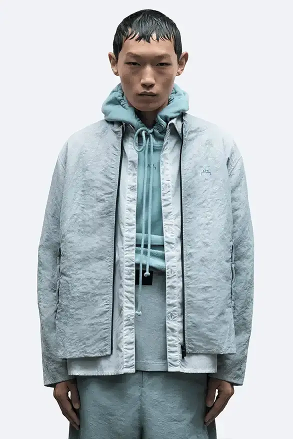 RADIO ECHOES: A-COLD-WALL* TUNES INTO UK ROOTS FOR SS25 pic of A-COLD-WALL*'s Spring/Summer 2025 collection called "Pink Noise," which draws inspiration from British radio culture. The piece describes the collection's technical outerwear, including utility jackets with toggles and drawstrings, ice blue collared jackets paired with loose shirts, color-blocked knitwear in black, brown and cream, graphic t-shirts, ribbed vests, and practical sling bags. The article notes that this collection follows the departure of founder Samuel Ross and the brand's acquisition by Four Marketing. The collection maintains A-COLD-WALL*'s signature gorpcore aesthetic with functional designs and is currently available on the brand's website. (image 7 of 9)