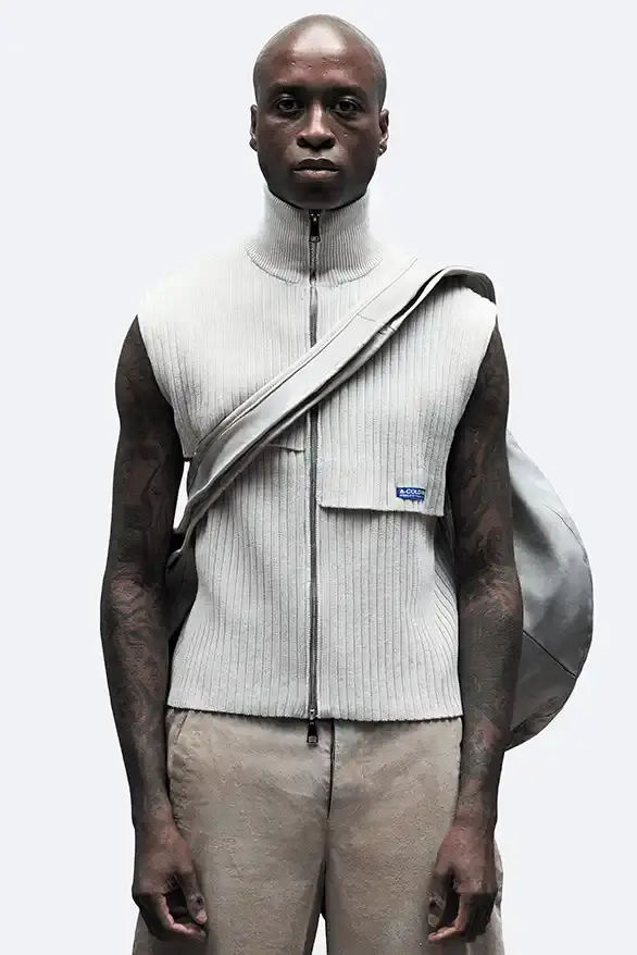RADIO ECHOES: A-COLD-WALL* TUNES INTO UK ROOTS FOR SS25 pic of A-COLD-WALL*'s Spring/Summer 2025 collection called "Pink Noise," which draws inspiration from British radio culture. The piece describes the collection's technical outerwear, including utility jackets with toggles and drawstrings, ice blue collared jackets paired with loose shirts, color-blocked knitwear in black, brown and cream, graphic t-shirts, ribbed vests, and practical sling bags. The article notes that this collection follows the departure of founder Samuel Ross and the brand's acquisition by Four Marketing. The collection maintains A-COLD-WALL*'s signature gorpcore aesthetic with functional designs and is currently available on the brand's website. (image 2 of 9)