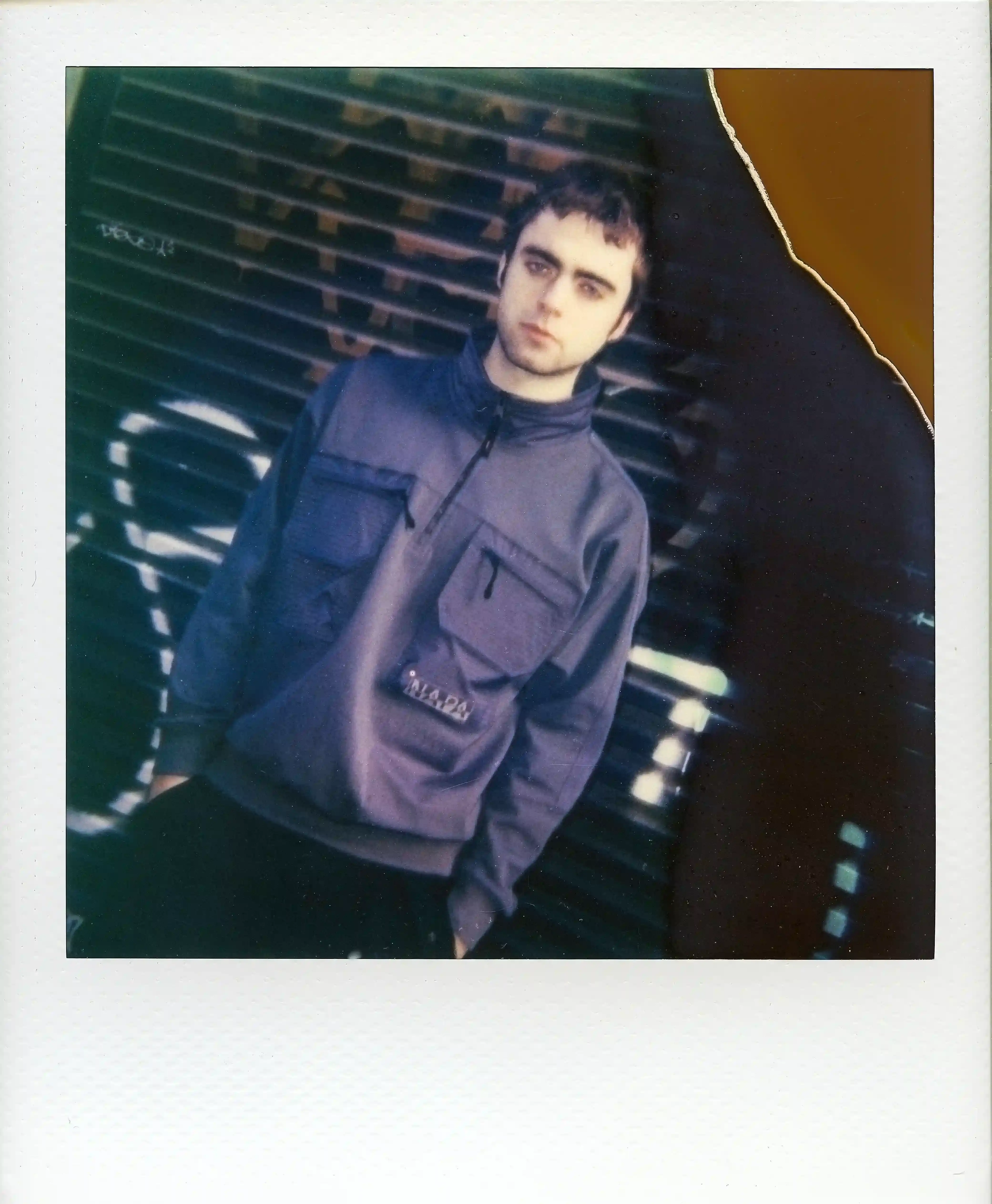 © Casawi | quadronnodistrict image of Lennon Gallagher, featuring a Q&A format discussion about his modeling work with Napapijri, his band activities, daily routines, and personal influences including David Bowie. The article reveals his casual approach to life, balancing music practice with modeling, and his preference for a laid-back lifestyle. shoot by quadronnodistrict