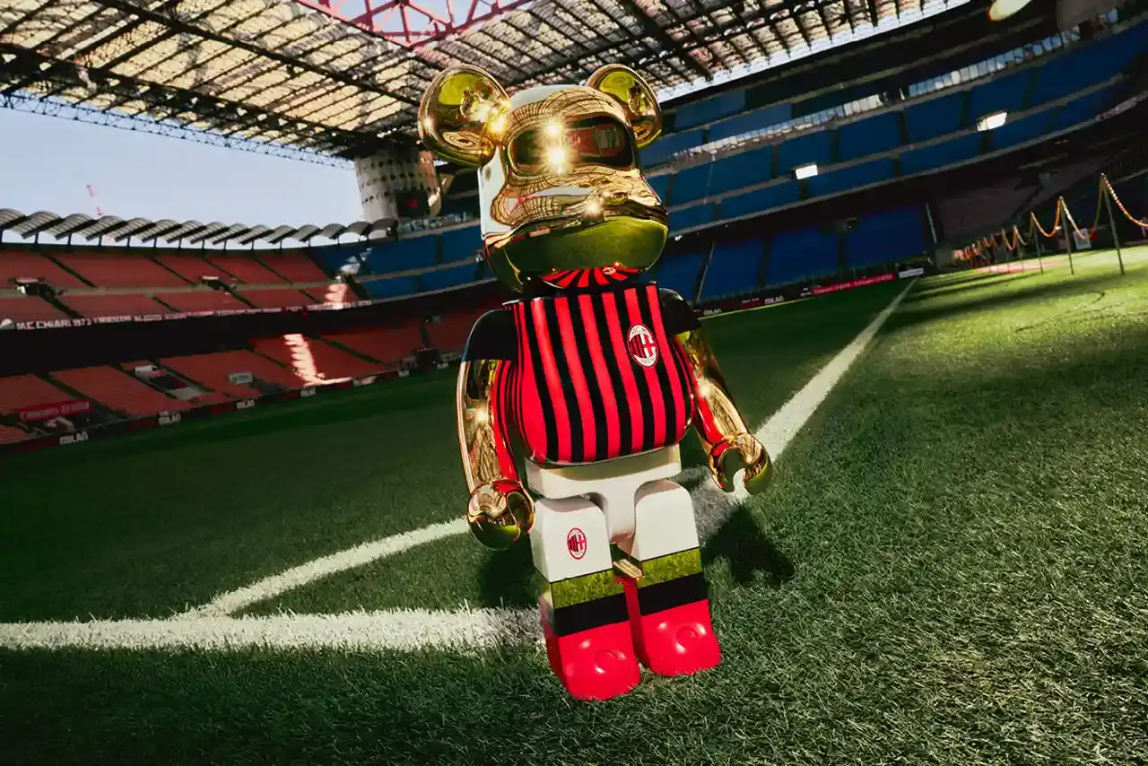 AC MILAN TEAMS UP WITH MEDICOM TOY FOR ANNIVERSARY COLLECTION AC Milan celebrates its 125th anniversary with a special edition BE@RBRICK collaboration, featuring collectible figures in the club’s iconic red and black stripes. The partnership with Medicom Toy includes BE@RBRICK figures in three sizes: 100%, 400%, and 1000%, all adorned with AC Milan’s traditional home kit design and finished in metallic gold. This collection honors the club’s rich legacy in Italian football, boasting 19 Serie A titles. The design contrasts with the fierce image envisioned by founder Herbert Kilpin, who described the team as “devils” in “red like fire and black like fear.” This collaboration adds to AC Milan’s cultural partnerships, including ties with Off-White™, minority stakeholders Drake and LeBron James, and previous collaborations with the New York Yankees. Available now on AC Milan’s online store, the limited edition 1000% figure is priced at €1,250 ($1,379), and the 400% and 100% set at €280 ($319)