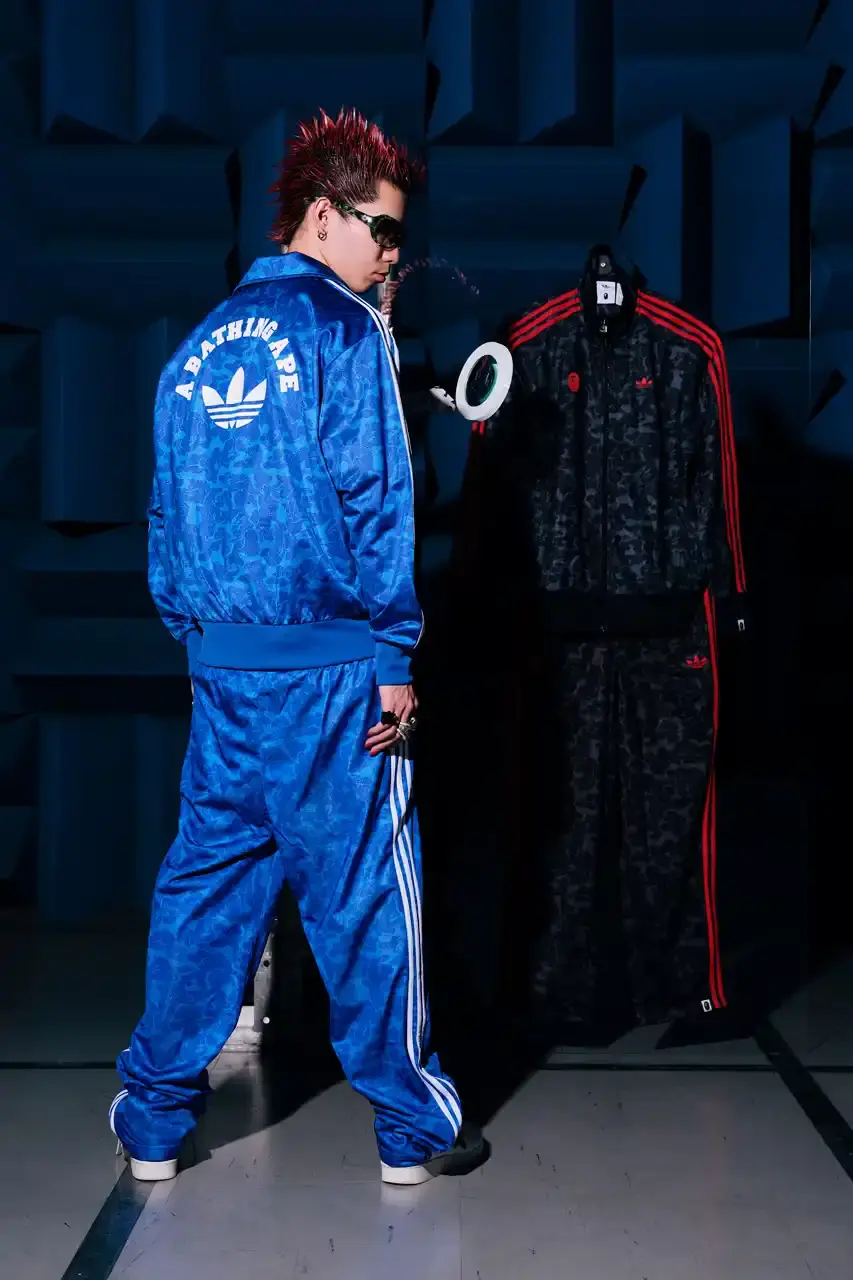 ADIDAS AND BAPE UNITE FOR FRESH COLLECTION AFTER TWO DECADES This article discusses the new collaboration between adidas and A Bathing Ape (BAPE). It details their latest capsule collection centered around the SSTR V BAPE sneaker, which reimagines the classic Superstar silhouette. The article describes the sneaker's design features, available colorways for adults and children, and mentions the accompanying apparel and accessories including tracksuits, hoodies, t-shirts, caps, pouches, and socks. It concludes with information about the April 5th release date through the CONFIRMED app and select retailers. (image 10 of 11)