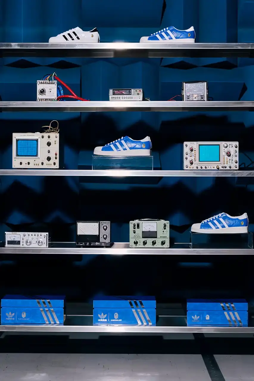 ADIDAS AND BAPE UNITE FOR FRESH COLLECTION AFTER TWO DECADES This article discusses the new collaboration between adidas and A Bathing Ape (BAPE). It details their latest capsule collection centered around the SSTR V BAPE sneaker, which reimagines the classic Superstar silhouette. The article describes the sneaker's design features, available colorways for adults and children, and mentions the accompanying apparel and accessories including tracksuits, hoodies, t-shirts, caps, pouches, and socks. It concludes with information about the April 5th release date through the CONFIRMED app and select retailers. (image 11 of 11)