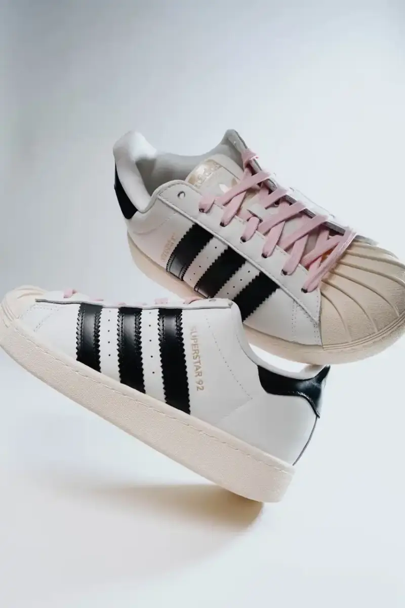 A Ma Maniére The Pharrell x adidas Virginia Superstar 92 sneaker in Off White colorway, showing its oversized silhouette with thick padding and classic shell toe design against a neutral background. (image 2 of 6)