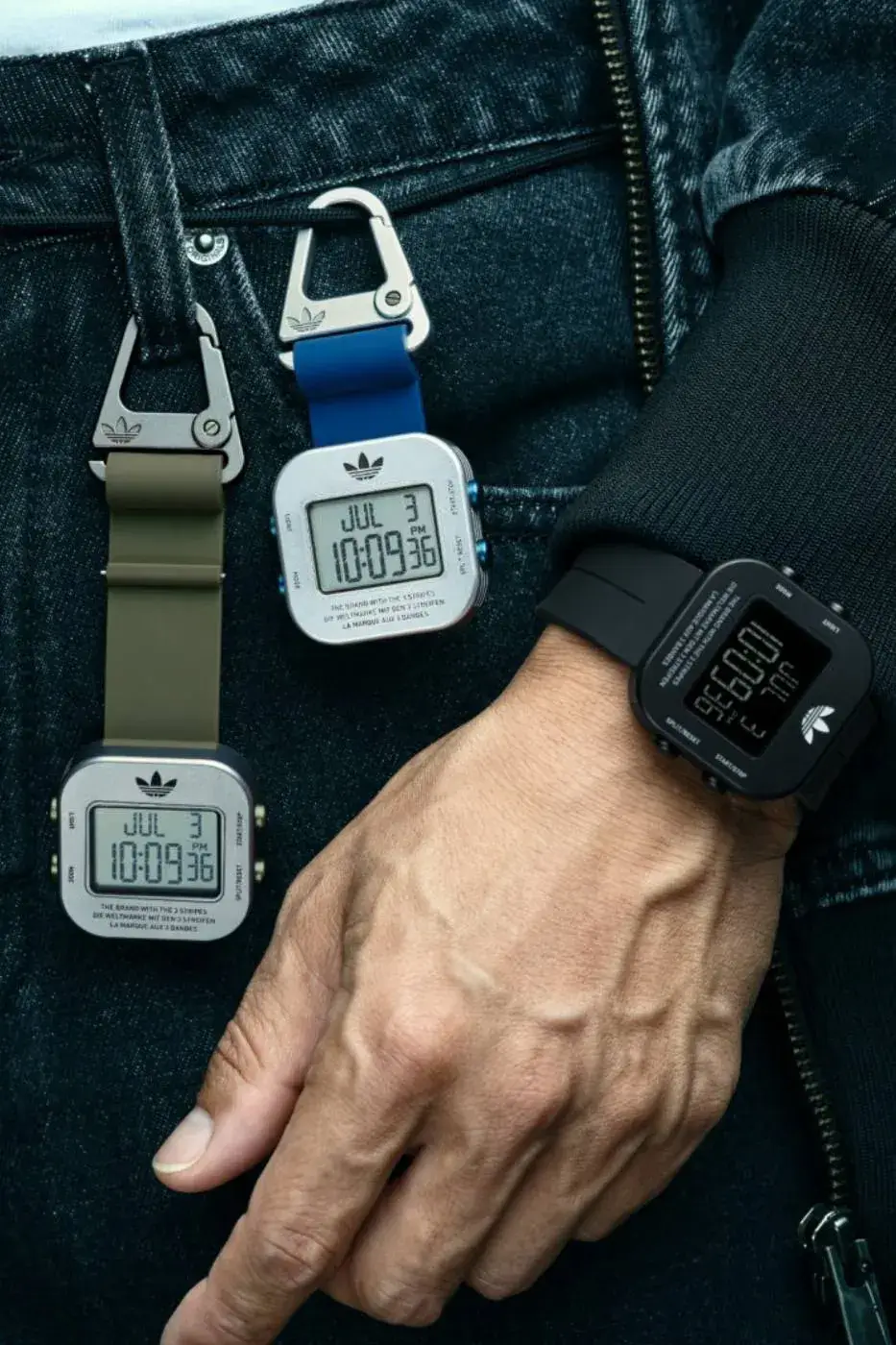 ADIDAS ORIGINALS ADAPTIK ONE TWO-WAY CARABINER WATCH The adidas Originals ADAPTIK ONE modular digital wristwatch shown with silicone straps and an aluminum carabiner clip attachment.