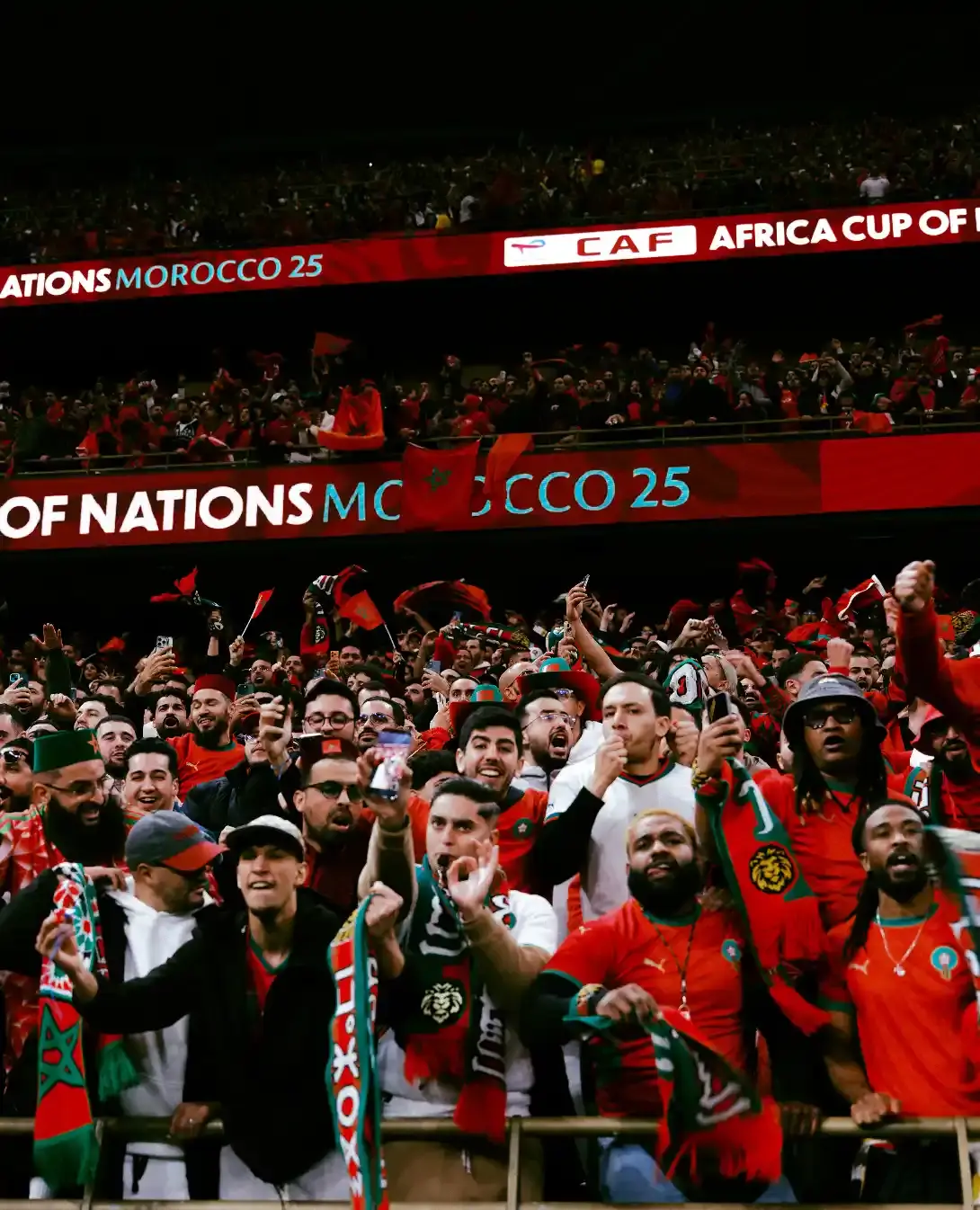 AFCON 2025 AND THE MOMENT FOOTBALL BECAME CULTURE Image photographs by Miguel the Colored Cowboy capture AFCON 2025 supporters in streets and stadiums. Images show clothing worn with purpose. Jerseys, tailored pieces, traditional fabrics, and sportswear appear across the frames. Faces show tension, pride, and focus. Clothing looks lived in. Scarves, jackets, and footwear respond to weather and movement. No staging. No distance. The gallery documents how style serves the moment during match days. Each image places viewers inside the crowd where expression stays personal and presence stays shared. (image 7 of 9)