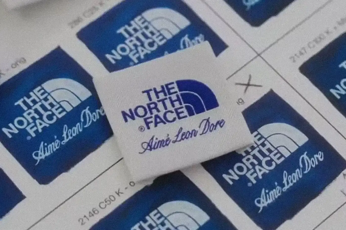 Video montage showing an Aimé Leon Dore x The North Face patchwork windbreaker being worn on a speedboat in Greek waters, interspersed with scenes from New York and London streets, and glimpses of past collaborations with Porsche and New Balance. The footage transitions between urban settings and Mediterranean seascapes.
