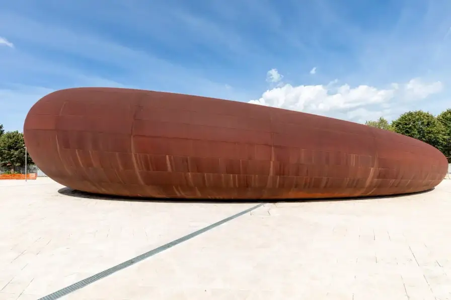 ANISH KAPOOR'S NAPLES SUBWAY STATION OPENS TODAY Two contrasting subway station entrances in Naples designed by Anish Kapoor: one features curved weathering steel panels with organic texture rising from plaza pavement, the other shows a sunken aluminum tube entrance with brushed metal finish reflecting surrounding buildings (image 2 of 7)