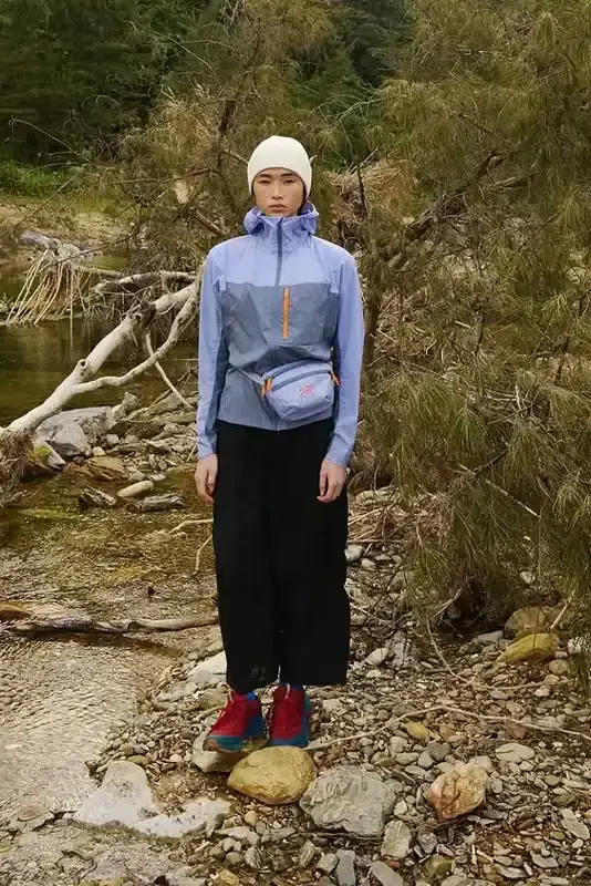 ARC'TERYX ARC'TERYX x BEAMS BOY Twilight Trail collection featuring lavender and yellow Beta Jackets, Squamish Hoodies, Mantis 1 Waist Packs, and Mantis 26 Backpacks arranged on a neutral background. (image 3 of 7)