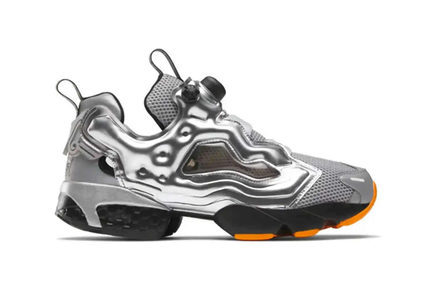 Aries/Reebok A pair of Aries x Reebok Instapump Fury 94 sneakers featuring a metallic silver upper with orange accents, showcasing the innovative laceless design and split-sole silhouette against a clean background.