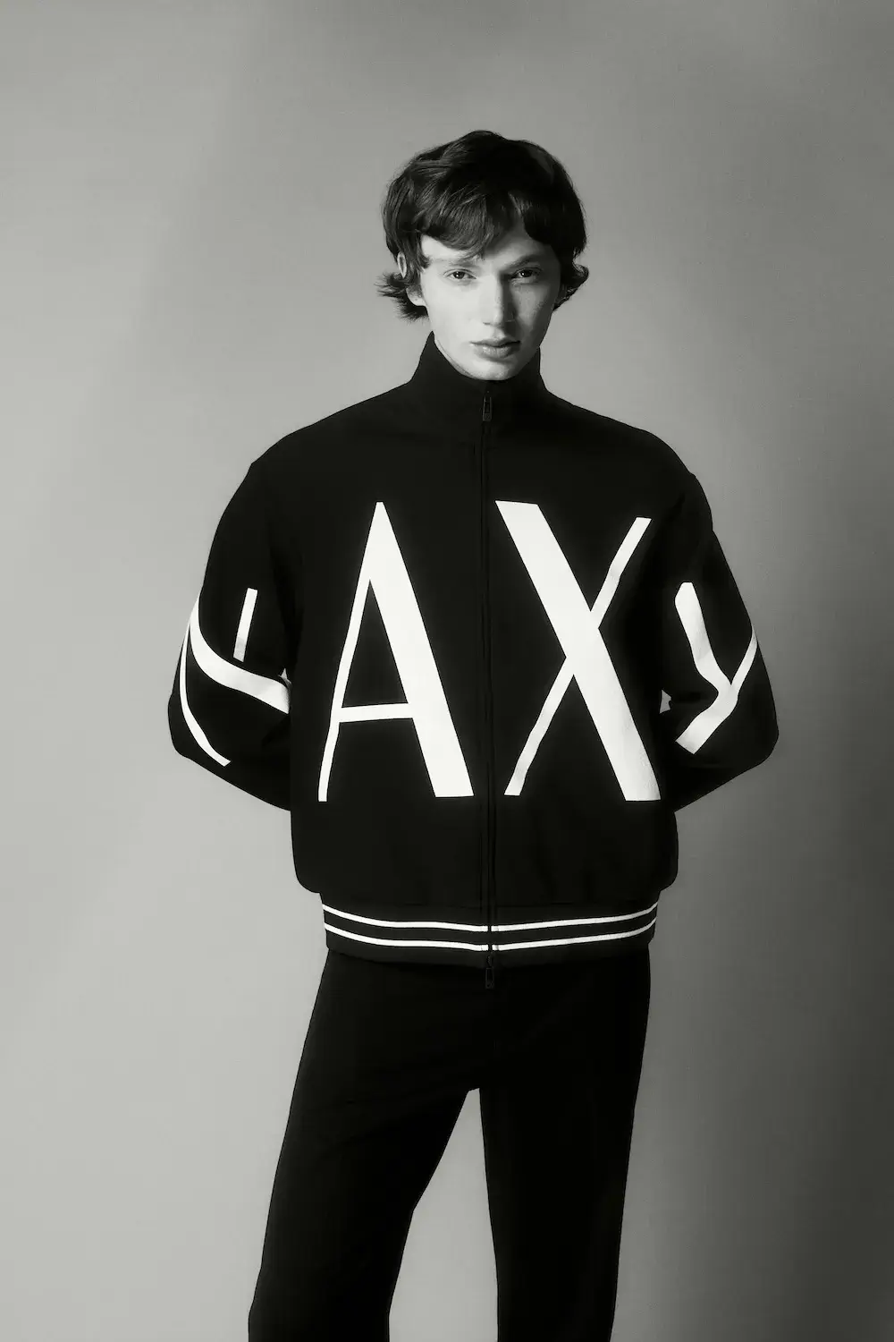 ARMANI EXCHANGE RELAUNCHES BASICS CAMPAIGN Black and white portrait photography from the Armani Exchange Basics campaign set against a neutral studio background. (image 9 of 16)