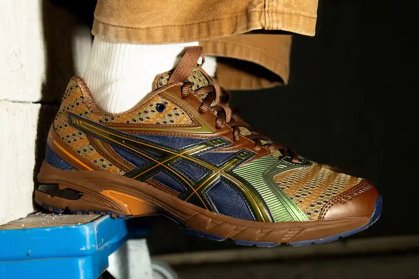 Asics ASICS GEL-DS Trainer 14 sneaker designed by Kiko Kostadinov, showing asymmetrical lacing system and multi-textured upper in gradient colorways. Four shoes displayed featuring Waterfall, Desert Camp, Dark Mustard, and Midnight color combinations.