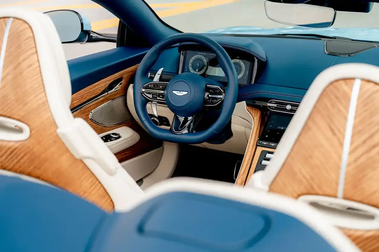ASTON MARTIN CREATES BESPOKE DB12 FOR FLORIDA MARKET image of Aston Martin's custom DB12 Volante convertible designed for the Florida market, featuring specialized blue paint with glass particles, white accent striping, and interior elements inspired by Palm Beach including palm leaf motifs and regional coordinates. (image 7 of 13)
