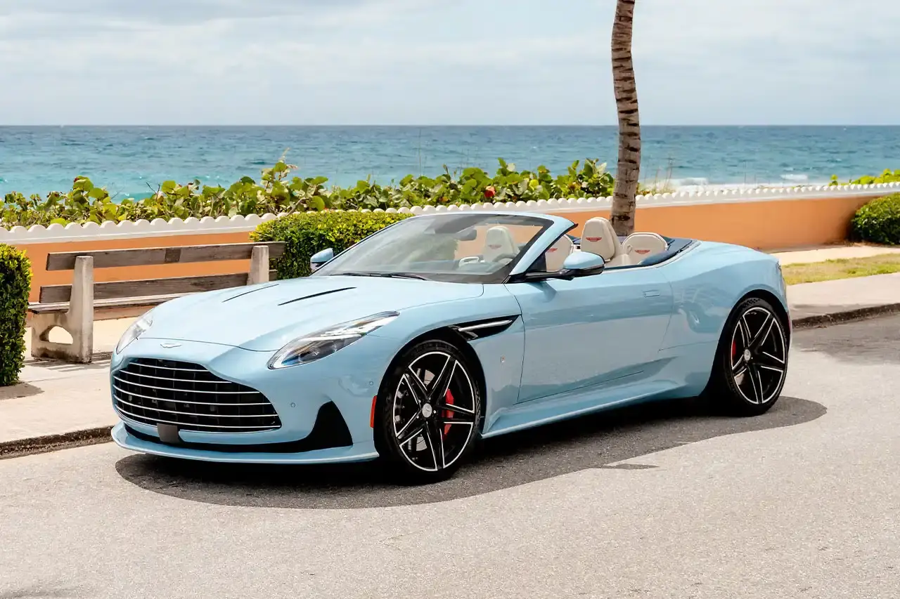 ASTON MARTIN CREATES BESPOKE DB12 FOR FLORIDA MARKET image of Aston Martin's custom DB12 Volante convertible designed for the Florida market, featuring specialized blue paint with glass particles, white accent striping, and interior elements inspired by Palm Beach including palm leaf motifs and regional coordinates. (image 2 of 13)