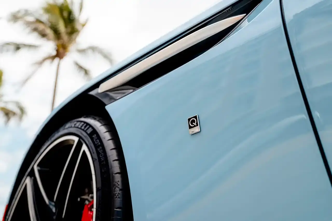 ASTON MARTIN CREATES BESPOKE DB12 FOR FLORIDA MARKET image of Aston Martin's custom DB12 Volante convertible designed for the Florida market, featuring specialized blue paint with glass particles, white accent striping, and interior elements inspired by Palm Beach including palm leaf motifs and regional coordinates. (image 5 of 13)