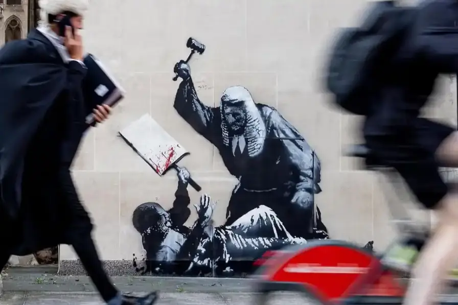 BANKSY TARGETS LONDON COURT BUILDING Banksy mural on court building exterior showing judge with gavel striking down protestor (image 2 of 2)