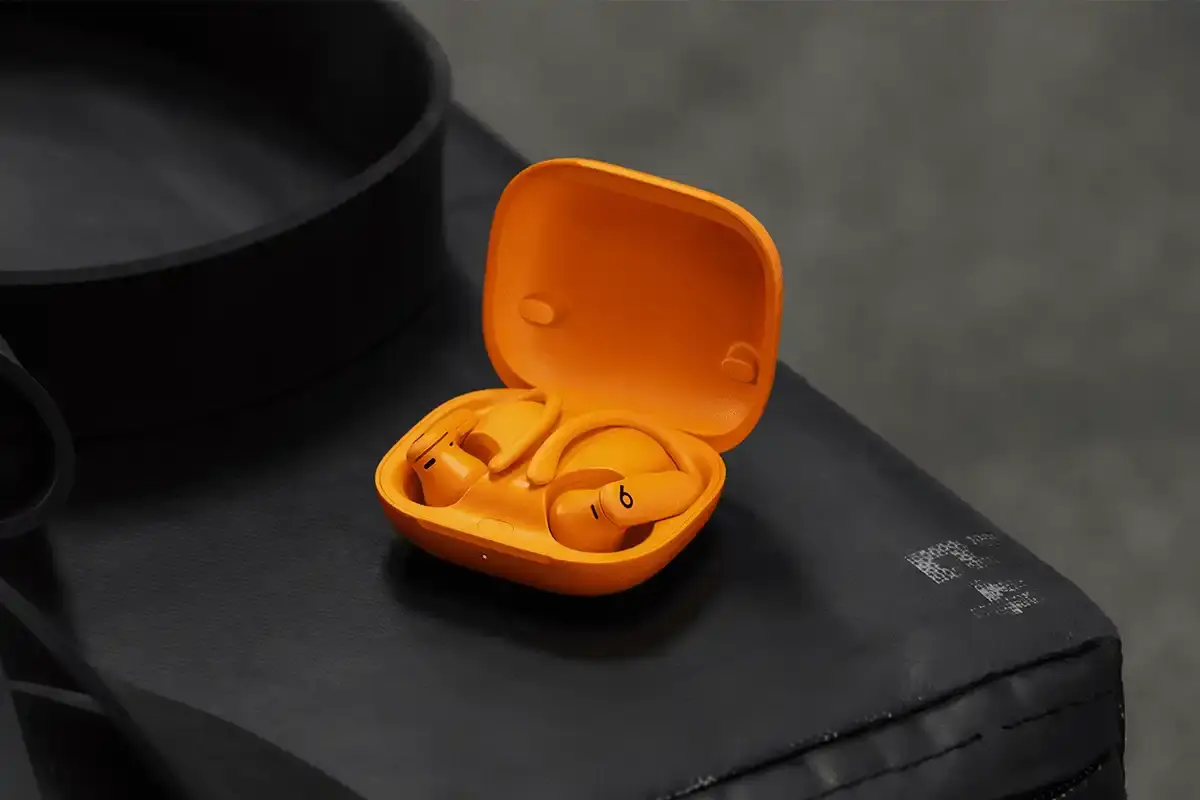 Beats Powerbeats Pro 2 wireless earphones in Electric Orange color, showing ear hooks and charging case with wireless charging capability. (image 5 of 8)