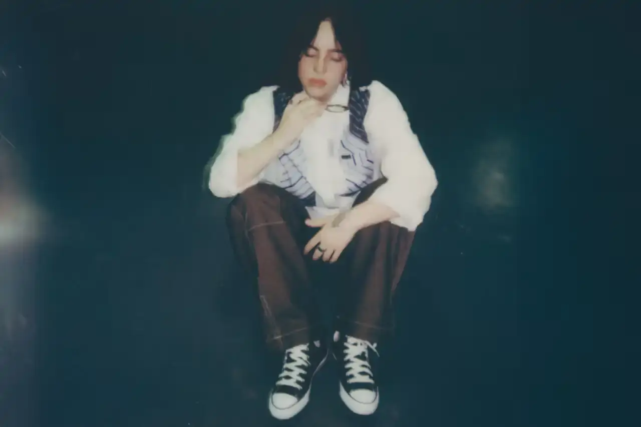 BILLIE EILISH COLLABORATES WITH CONVERSE ON CUSTOMIZABLE SNEAKER LINE Billie Eilish partners with Converse to launch a customizable sneaker line featuring personalized Chuck Taylor All Star and Chuck Taylor Lift Platform models. The collection includes ice-blue transparent soles with Eilish's album name, options to add song lyrics to midsoles, and various design elements like embroidered mascots and colored stars. Available exclusively on Converse's website, this collaboration offers fans a unique way to express themselves through personalized footwear inspired by Eilish's music and style. (image 3 of 7)