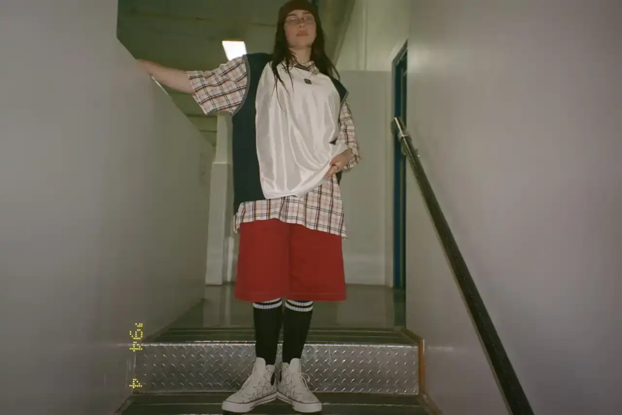 BILLIE EILISH COLLABORATES WITH CONVERSE ON CUSTOMIZABLE SNEAKER LINE Billie Eilish partners with Converse to launch a customizable sneaker line featuring personalized Chuck Taylor All Star and Chuck Taylor Lift Platform models. The collection includes ice-blue transparent soles with Eilish's album name, options to add song lyrics to midsoles, and various design elements like embroidered mascots and colored stars. Available exclusively on Converse's website, this collaboration offers fans a unique way to express themselves through personalized footwear inspired by Eilish's music and style. (image 6 of 7)