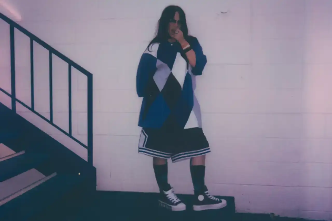BILLIE EILISH COLLABORATES WITH CONVERSE ON CUSTOMIZABLE SNEAKER LINE Billie Eilish partners with Converse to launch a customizable sneaker line featuring personalized Chuck Taylor All Star and Chuck Taylor Lift Platform models. The collection includes ice-blue transparent soles with Eilish's album name, options to add song lyrics to midsoles, and various design elements like embroidered mascots and colored stars. Available exclusively on Converse's website, this collaboration offers fans a unique way to express themselves through personalized footwear inspired by Eilish's music and style. (image 5 of 7)
