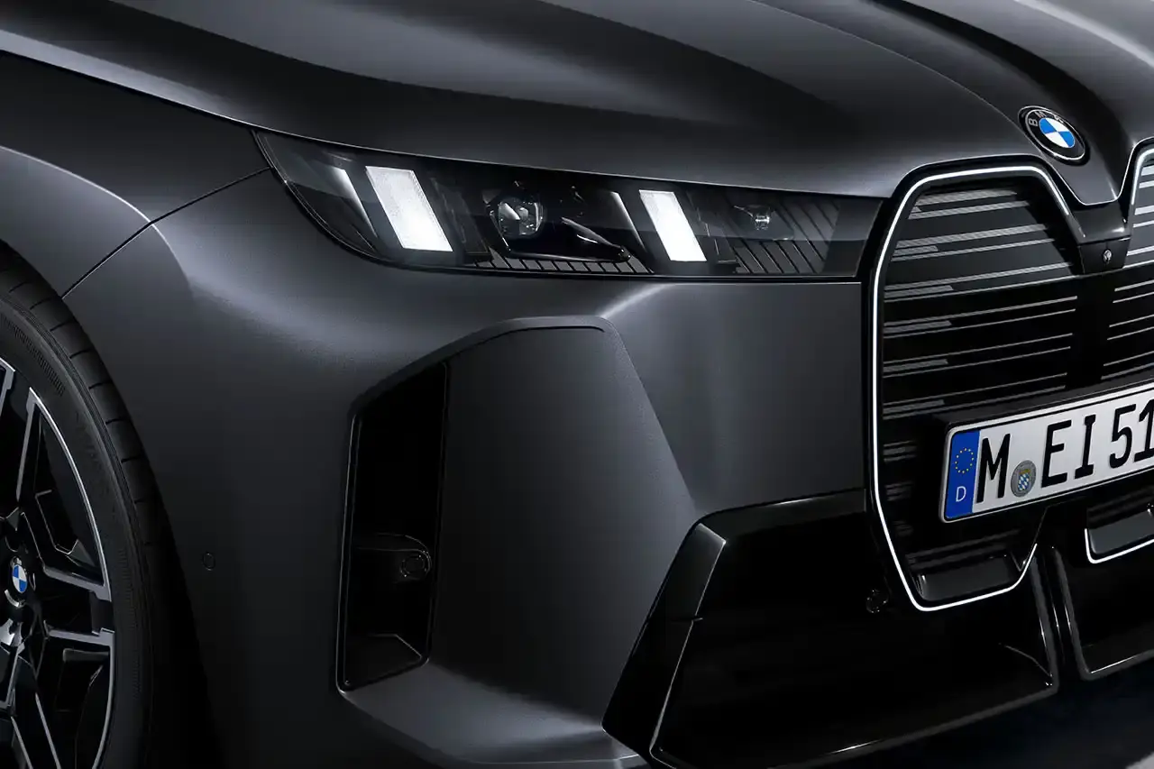 BMW BMW iX M70 xDrive electric SUV in front three-quarter view, showing darkened kidney grille with M badge and black exterior mirrors (image 6 of 11)