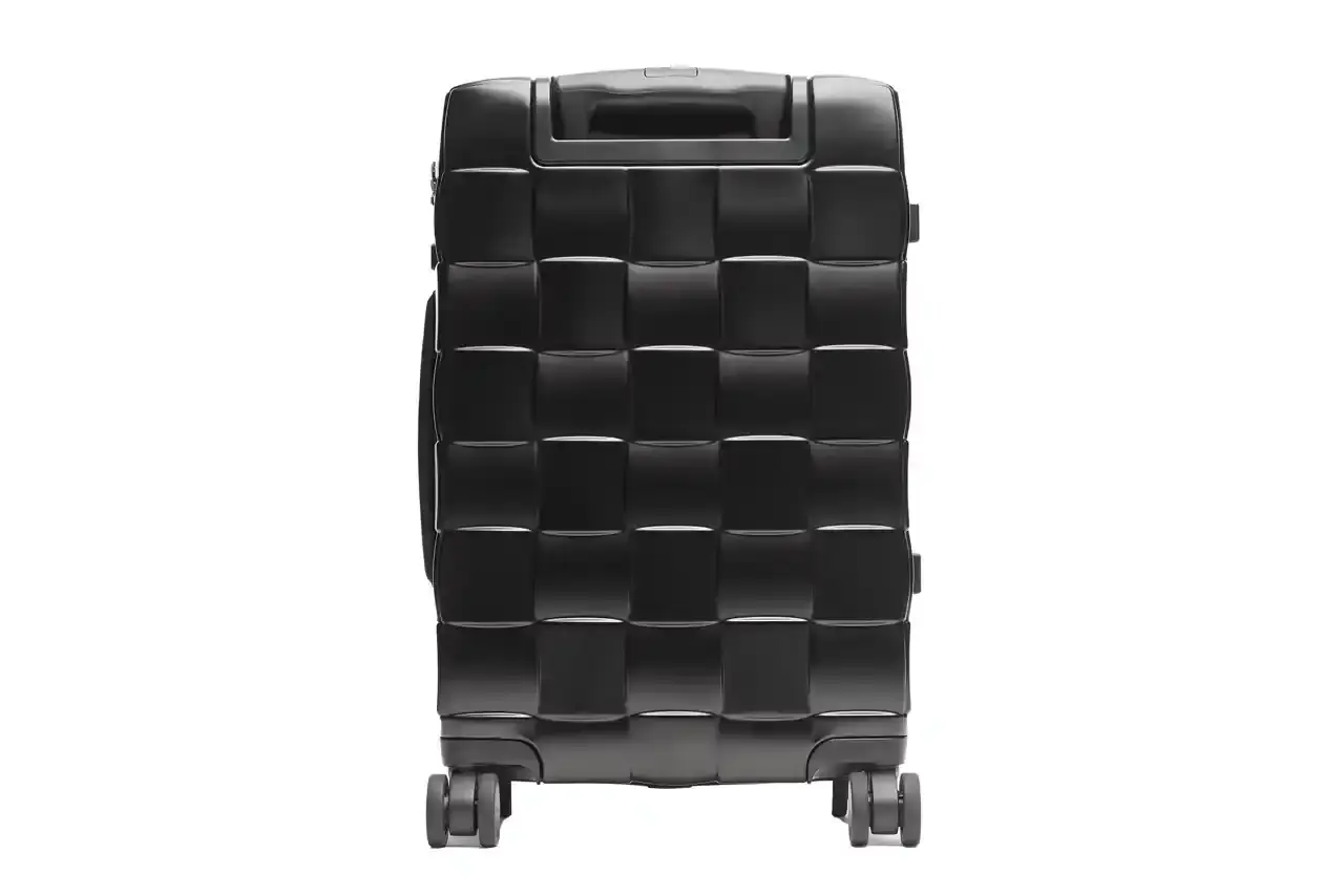Bottega Veneta Bottega Veneta Odyssey carry-on suitcase with textured polycarbonate shell featuring 3D Intreccio pattern, silver hardware, and brown calfskin leather handles. The wheeled luggage is shown in a three-quarter view displaying its structured design and branded details. (image 6 of 7)