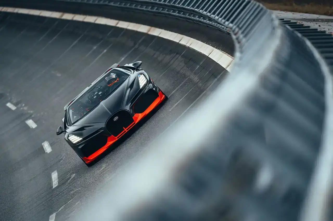 Bugatti Bugatti, the renowned manufacturer of high-performance luxury automobiles, has once again pushed the boundaries of automotive engineering with the remarkable achievements of its W16 Mistral model. On November 9th, the W16 Mistral set a new world record for the fastest open-top car, reaching a staggering speed of 453.91 km/h (281 mph) at the ATP Automotive Testing Papenburg track in Germany. The record-breaking run was piloted by Andy Wallace, Bugatti's official test driver and a renowned Le Mans winner, showcasing the exceptional capabilities of the W16 Mistral. This remarkable feat builds upon Bugatti's legacy of record-setting performance, including the Veyron 16.4 Grand Sport Vitesse's 408.84 km/h (253 mph) record achieved in 2013 and the Chiron Super Sport 300+'s 490.48 km/h (304 mph) closed-cockpit record set in 2019. The W16 Mistral, a bespoke $14.8 million USD model, features a striking black carbon body with "Jet Orange" accents, paying homage to Bugatti's previous record-setting vehicles. The event was attended by Mate Rimac, CEO of Bugatti Rimac, as well as Bugatti's senior team and the vehicle's owner, a collector from Punjab, India. Highlighting the W16 Mistral's prowess, the owner had the opportunity to experience the car's remarkable speed firsthand, joining Wallace for a high-speed run. This latest addition to The Singh Collection joins an exclusive lineup of Bugatti's record-breaking automobiles. (image 12 of 12)