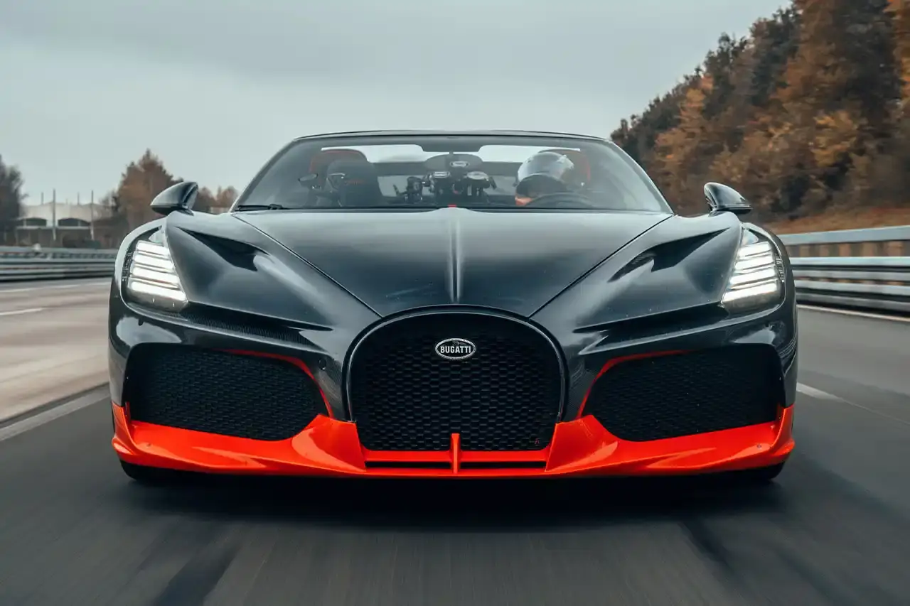 Bugatti Bugatti, the renowned manufacturer of high-performance luxury automobiles, has once again pushed the boundaries of automotive engineering with the remarkable achievements of its W16 Mistral model. On November 9th, the W16 Mistral set a new world record for the fastest open-top car, reaching a staggering speed of 453.91 km/h (281 mph) at the ATP Automotive Testing Papenburg track in Germany. The record-breaking run was piloted by Andy Wallace, Bugatti's official test driver and a renowned Le Mans winner, showcasing the exceptional capabilities of the W16 Mistral. This remarkable feat builds upon Bugatti's legacy of record-setting performance, including the Veyron 16.4 Grand Sport Vitesse's 408.84 km/h (253 mph) record achieved in 2013 and the Chiron Super Sport 300+'s 490.48 km/h (304 mph) closed-cockpit record set in 2019. The W16 Mistral, a bespoke $14.8 million USD model, features a striking black carbon body with "Jet Orange" accents, paying homage to Bugatti's previous record-setting vehicles. The event was attended by Mate Rimac, CEO of Bugatti Rimac, as well as Bugatti's senior team and the vehicle's owner, a collector from Punjab, India. Highlighting the W16 Mistral's prowess, the owner had the opportunity to experience the car's remarkable speed firsthand, joining Wallace for a high-speed run. This latest addition to The Singh Collection joins an exclusive lineup of Bugatti's record-breaking automobiles. (image 2 of 12)