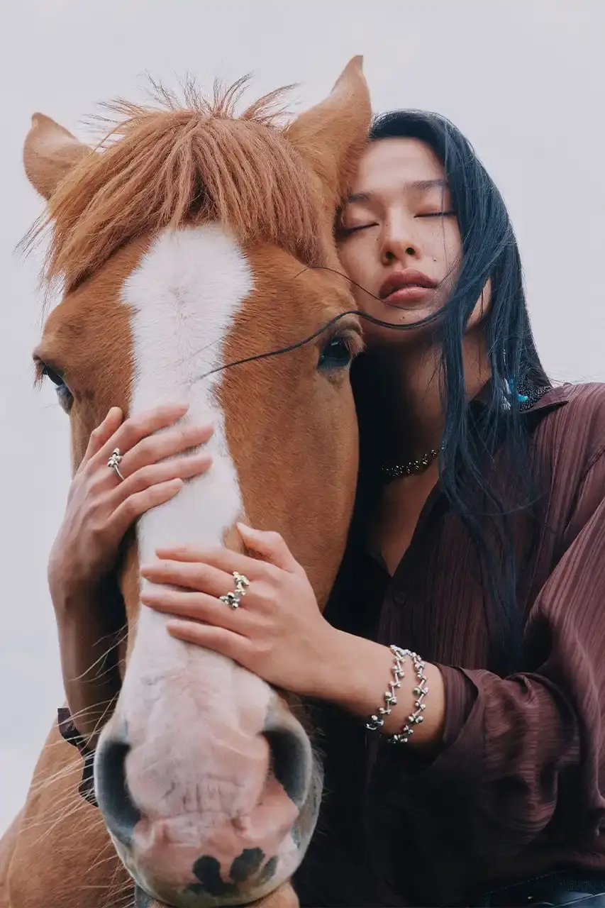 BYREDO MARKS LUNAR NEW YEAR WITH HORSE-THEMED CAMPAIGN Byredo releases Lunar New Year campaign featuring two fragrances, Rose of No Man's Land and Desert Dawn, photographed by Annie Lai with models Xi Yi and Wang Xuan in natural settings, drawing inspiration from Swedish Dala horse symbolism. (image 2 of 4)