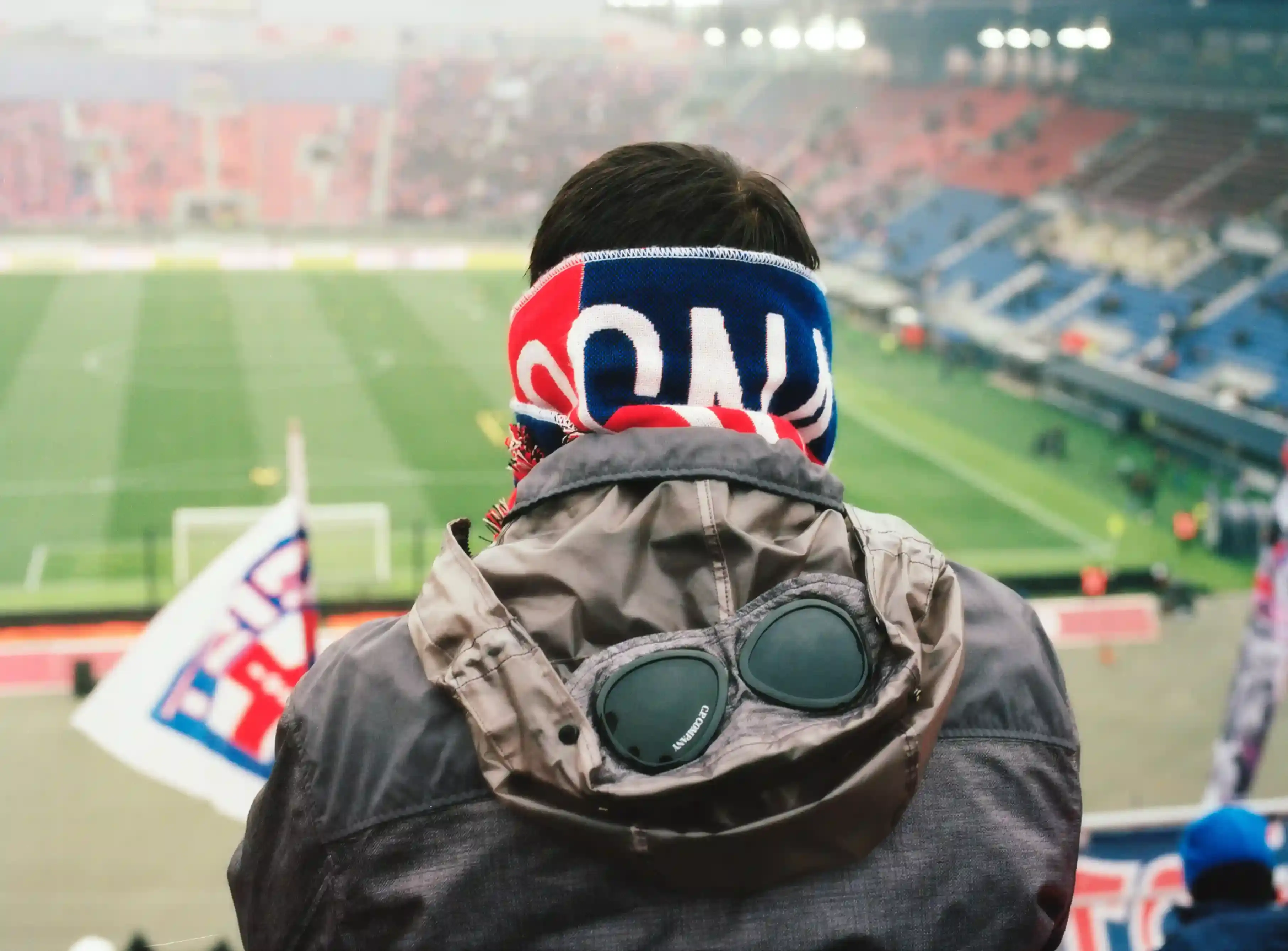 Image shows C.P. Company and Bologna FC logos, representing their new partnership, with a backdrop of Bologna's urban landscape and football stadium.