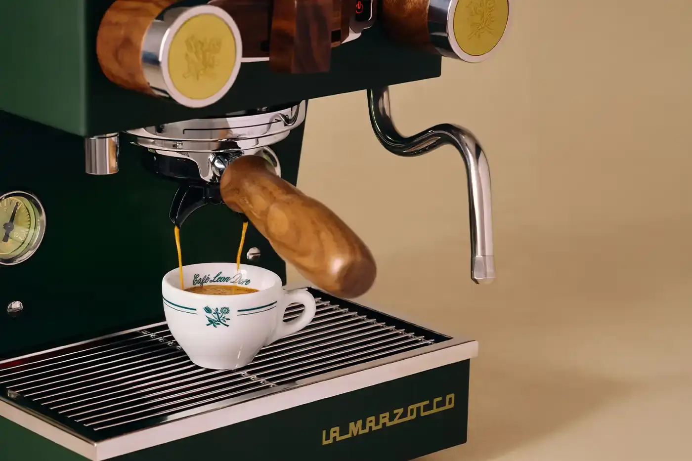 CAFÉ LEON DORE PARTNERS WITH LA MARZOCCO ON EXCLUSIVE COFFEE COLLECTION Image of the collaboration between Café Leon Dore (part of Aimé Leon Dore) and La Marzocco. The partnership features a custom-designed Linea Micra espresso machine in green with brass and walnut details, plus co-branded apparel including aprons, t-shirts, and hats. The collection is available exclusively through Aimé Leon Dore's stores and website. The article provides details about the machine's professional capabilities despite its compact size, and notes that it's being produced in limited quantities. (image 3 of 6)