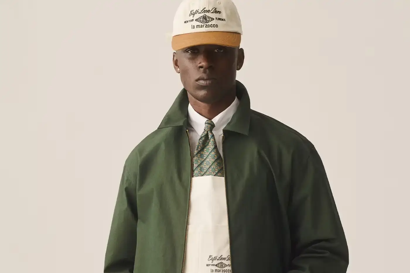 CAFÉ LEON DORE PARTNERS WITH LA MARZOCCO ON EXCLUSIVE COFFEE COLLECTION Image of the collaboration between Café Leon Dore (part of Aimé Leon Dore) and La Marzocco. The partnership features a custom-designed Linea Micra espresso machine in green with brass and walnut details, plus co-branded apparel including aprons, t-shirts, and hats. The collection is available exclusively through Aimé Leon Dore's stores and website. The article provides details about the machine's professional capabilities despite its compact size, and notes that it's being produced in limited quantities.