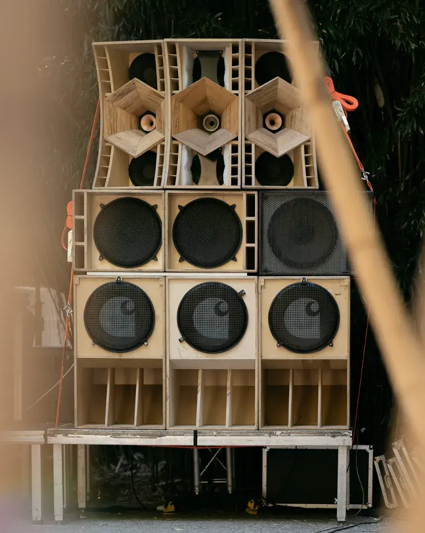 CARHARTT WIP JOINS USV AT LOST FESTIVAL 2026 A stacked wall of custom wooden speakers sits outdoors, featuring the Carhartt C logo on the grilles held together by orange straps. image by Stefano Mattea
