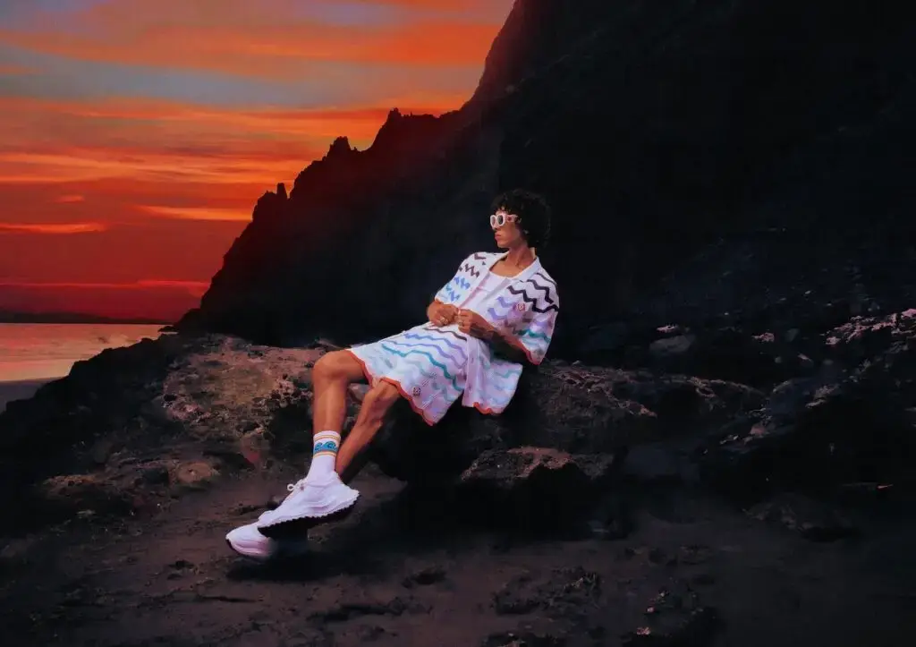 Casablanca Model relaxing on Tenerife beach at sunset wearing Casablanca Beach Club 2025 gradient monogram linen shirt and trousers (image 3 of 5)