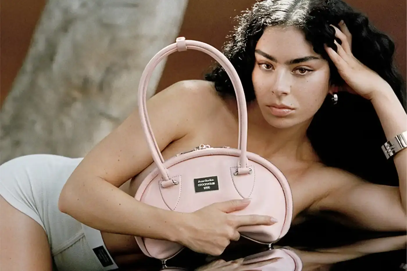 Talia Chetrit/Acne Studios The Acne Studios Spring/Summer 2025 campaign features singer-songwriter Charli XCX wearing key pieces from the collection, including coated iridescent and painted trompe-l'oeil denim styles, as well as the new season's Multipocket and Bowlina bags. The collaboration highlights Charli XCX's longstanding relationship with the brand and her ability to seamlessly blend underground and mainstream influences.