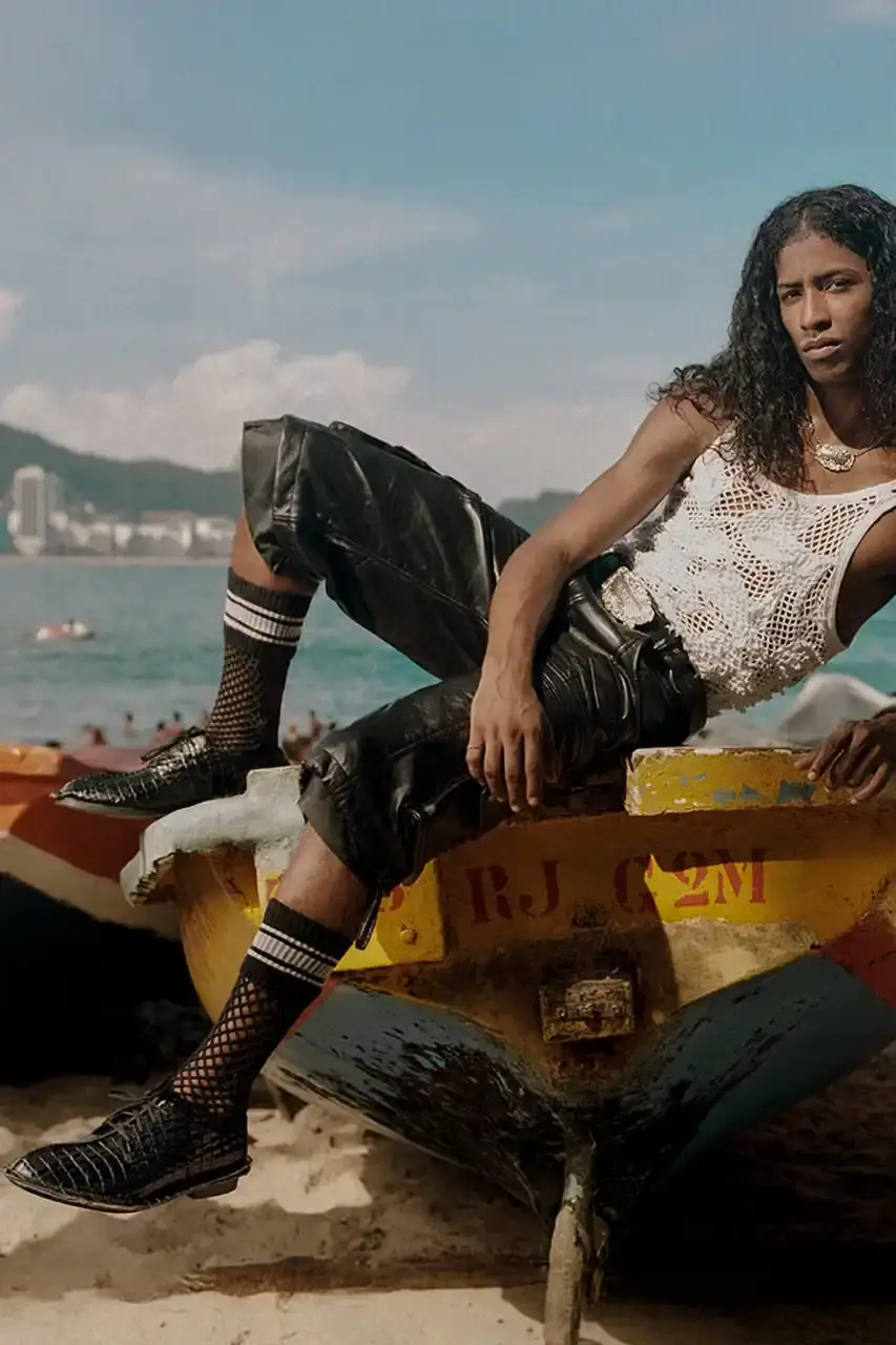 MARTINE ROSE RESHAPES CLARKS HERITAGE IN SS25 COLLECTION An image description for screen readers that highlights the key visual elements of the Clarks x Martine Rose SS25 campaign, focusing on the three shoe styles (Derby, Torview, and Heel) photographed on local beachgoers, showcasing the unique design details, textures, and color palette of the collection. (image 6 of 6)