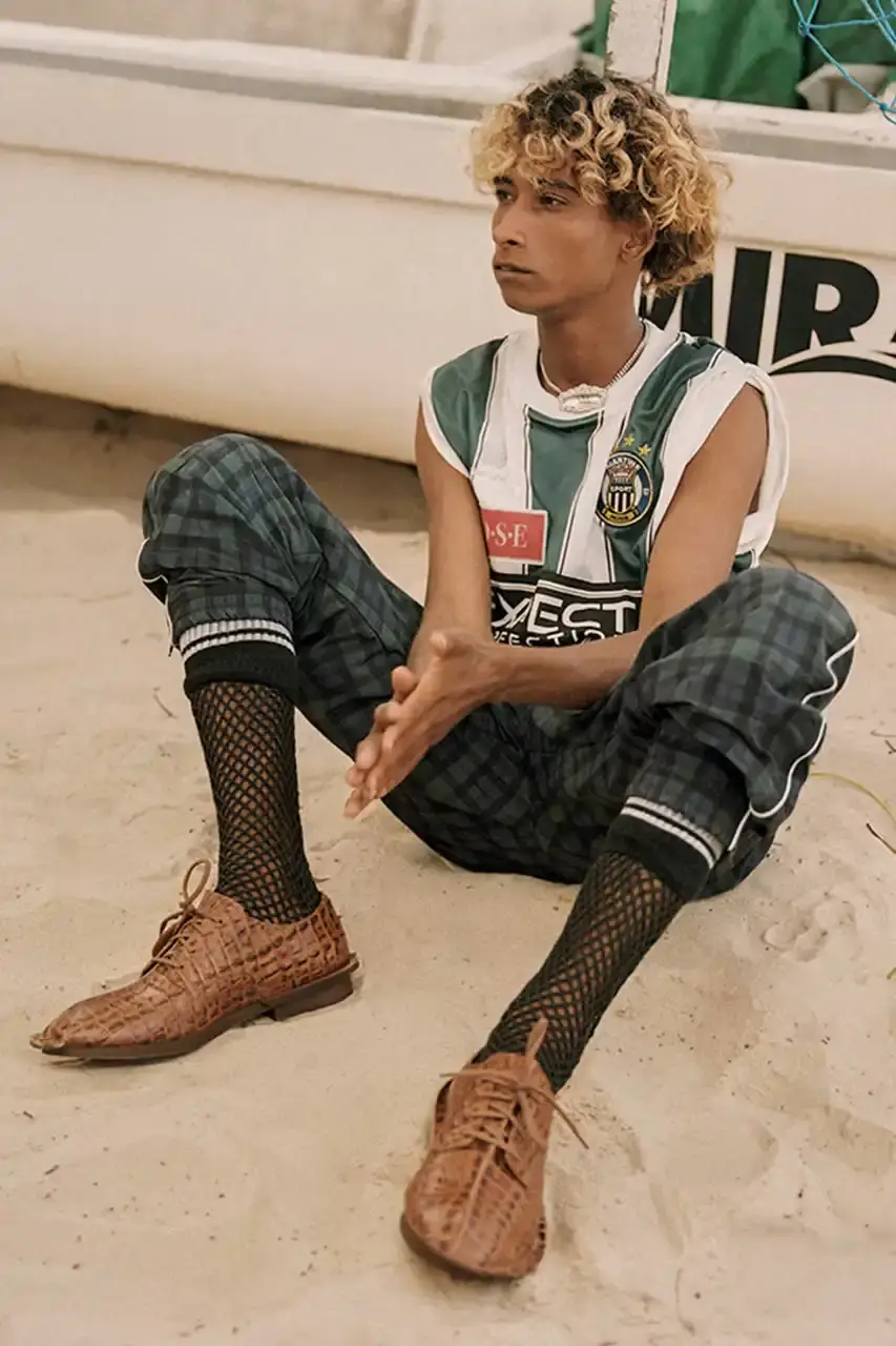MARTINE ROSE RESHAPES CLARKS HERITAGE IN SS25 COLLECTION An image description for screen readers that highlights the key visual elements of the Clarks x Martine Rose SS25 campaign, focusing on the three shoe styles (Derby, Torview, and Heel) photographed on local beachgoers, showcasing the unique design details, textures, and color palette of the collection. (image 5 of 6)