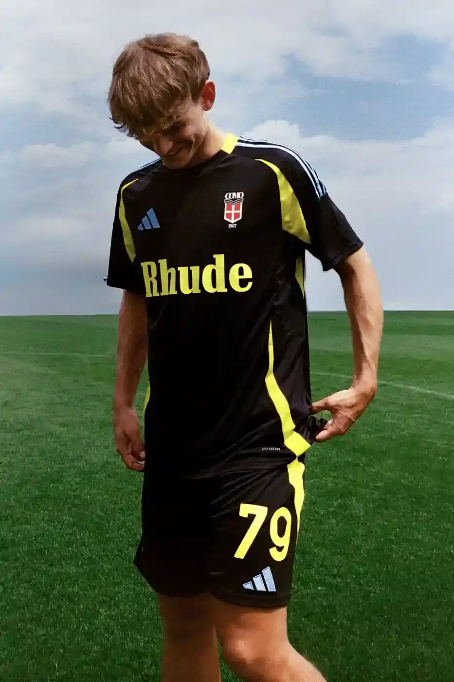 COMO 1907 LAUNCHES RHUDE-DESIGNED FOURTH KIT image about Italian football club Como 1907's new jersey collaboration with fashion brand Rhude and Adidas. The limited-edition black and gold kit celebrates the team's return to Serie A after 21 years and combines Italian lakeside heritage with Los Angeles street fashion aesthetics. Priced at €275, the jersey features technical fabric and special branding elements.