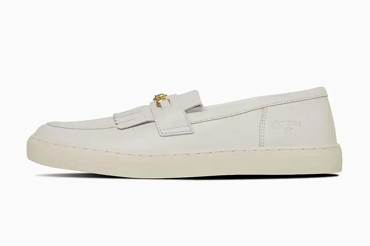 Converse Converse All-Star Coupe GB Loafer shown from side angle, featuring minimalist leather construction, tasseled midfoot strap with embossed star details, and classic Converse sole. Available in black and off-white colorways. (image 8 of 8)