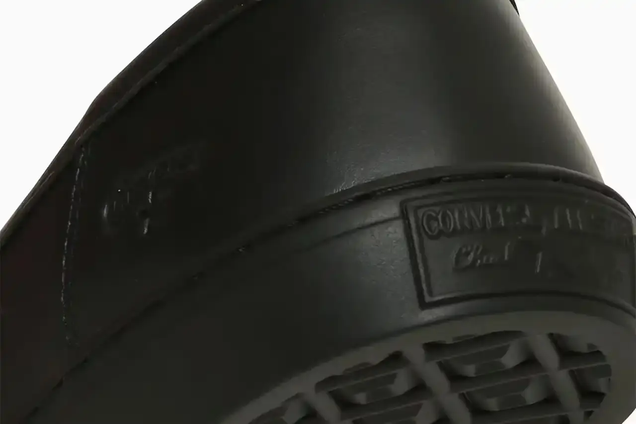 Converse Converse All-Star Coupe GB Loafer shown from side angle, featuring minimalist leather construction, tasseled midfoot strap with embossed star details, and classic Converse sole. Available in black and off-white colorways. (image 3 of 8)