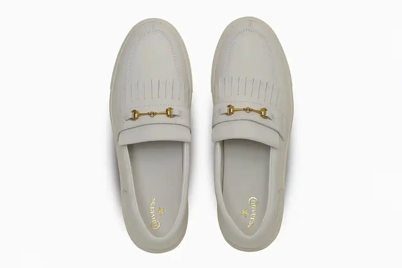 Converse Converse All-Star Coupe GB Loafer shown from side angle, featuring minimalist leather construction, tasseled midfoot strap with embossed star details, and classic Converse sole. Available in black and off-white colorways. (image 7 of 8)