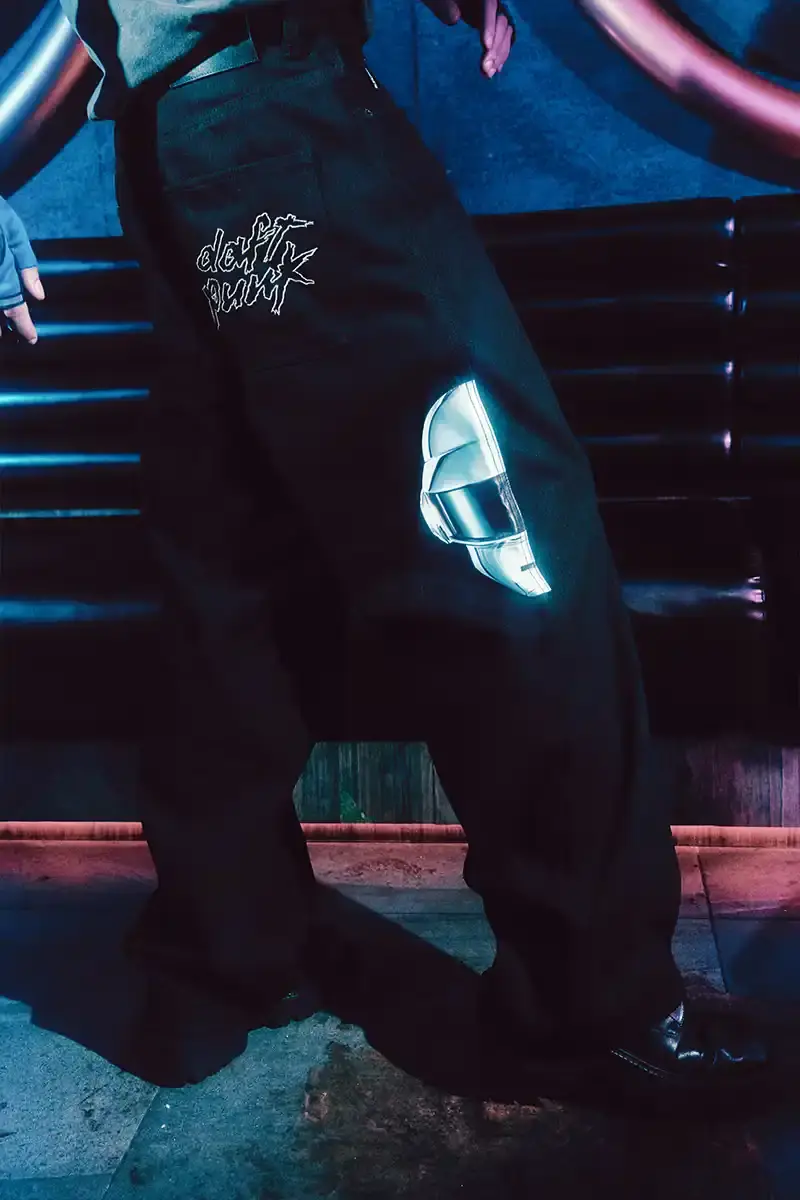 DAFT PUNK TEAMS UP WITH PLEASURES FOR NEW CAPSULE image about fashion collaboration between electronic music duo Daft Punk and streetwear brand PLEASURES. Features clothing and accessories incorporating the musicians' robot helmet imagery, album artwork, and references to their music videos and films. Collection includes hoodies, jackets, jeans, and accessories available July 16, 2025. (image 11 of 28)