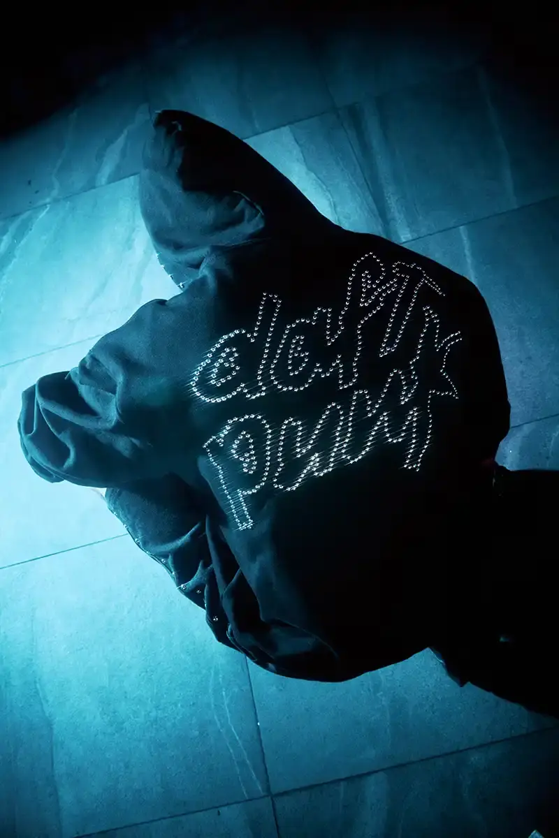 DAFT PUNK TEAMS UP WITH PLEASURES FOR NEW CAPSULE image about fashion collaboration between electronic music duo Daft Punk and streetwear brand PLEASURES. Features clothing and accessories incorporating the musicians' robot helmet imagery, album artwork, and references to their music videos and films. Collection includes hoodies, jackets, jeans, and accessories available July 16, 2025. (image 4 of 28)