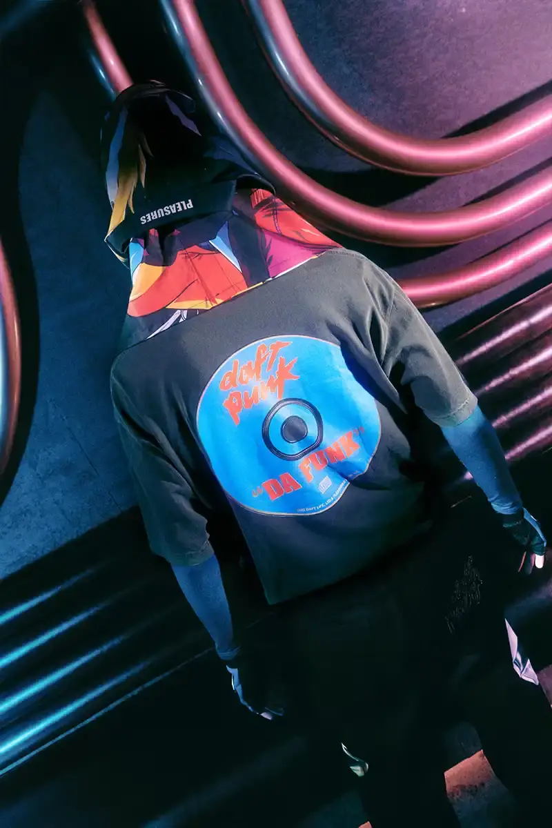 DAFT PUNK TEAMS UP WITH PLEASURES FOR NEW CAPSULE image about fashion collaboration between electronic music duo Daft Punk and streetwear brand PLEASURES. Features clothing and accessories incorporating the musicians' robot helmet imagery, album artwork, and references to their music videos and films. Collection includes hoodies, jackets, jeans, and accessories available July 16, 2025. (image 14 of 28)