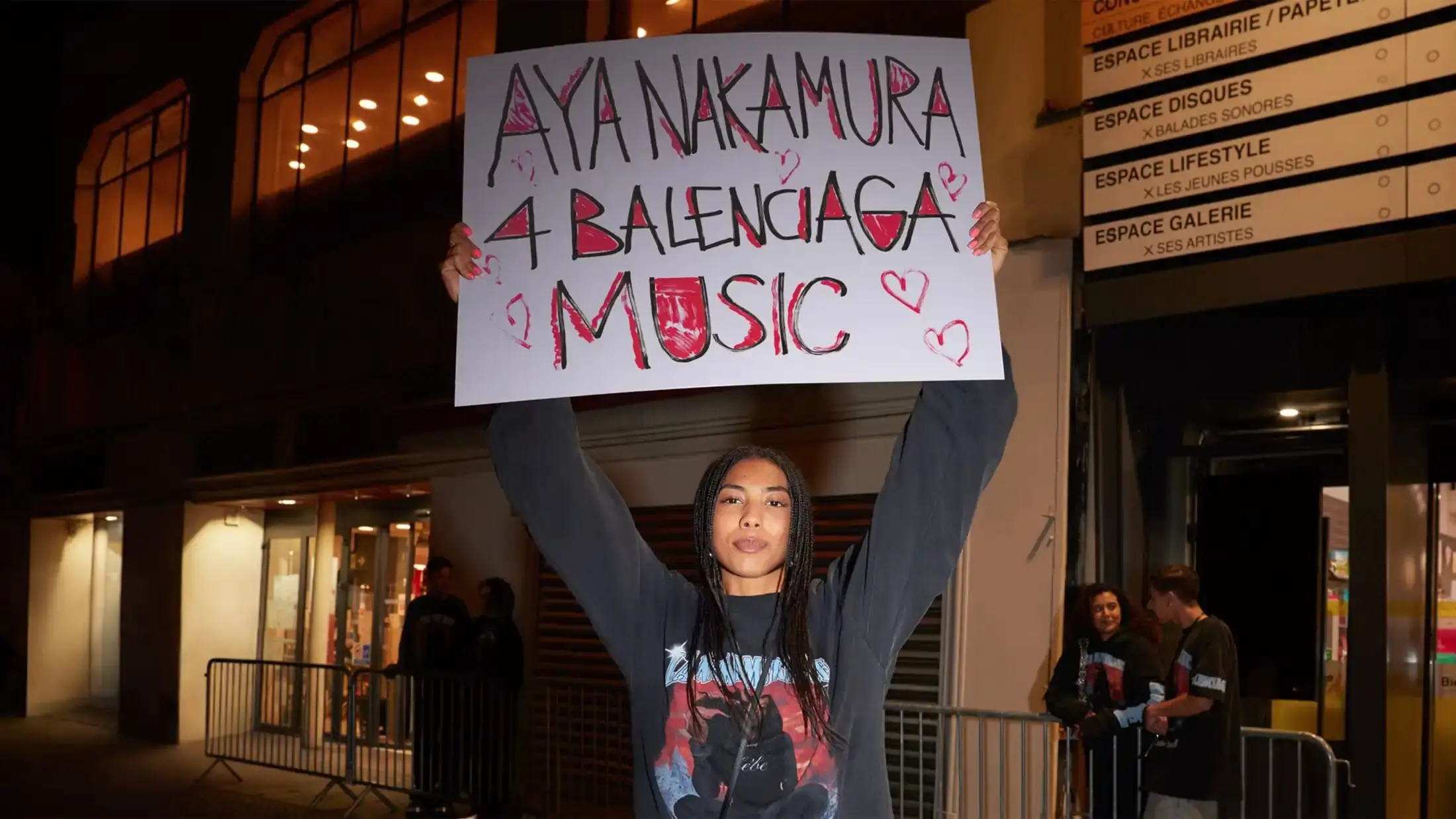 Aya Nakamura, a Malian-born French singer, posing in a stylish outfit. She is known for her chart-topping hits and collaboration with Balenciaga