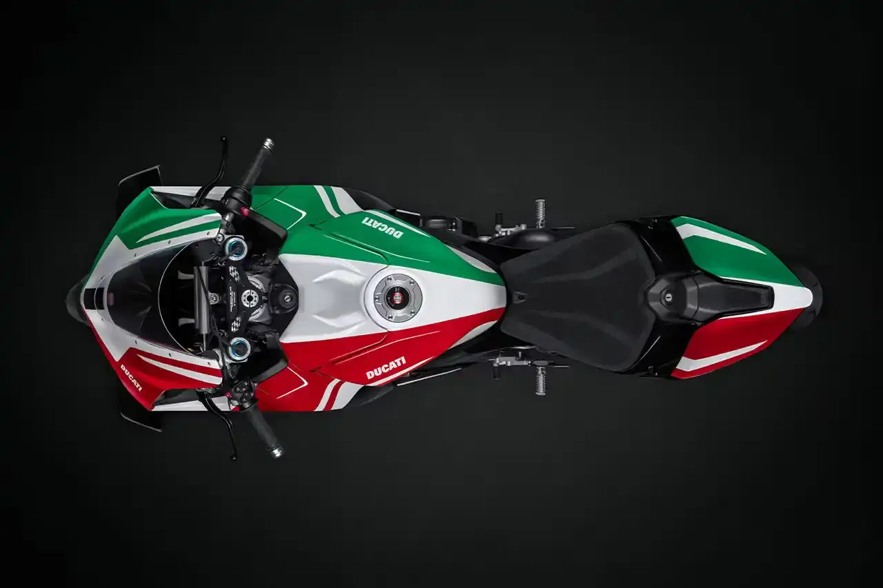 Ducati A side profile view of the Ducati Panigale V4 Tricolore motorcycle, showcasing its sleek racing design with asymmetrical Italian flag-inspired color scheme. The bike features carbon fiber rims, a racing-inspired silhouette, and a distinctive checkered flag motif, highlighting its special edition status and high-performance engineering. (image 5 of 7)