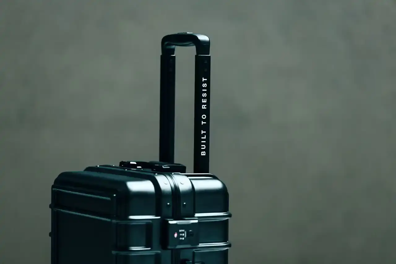 Eastpak Resist'r Case hard-shell luggage in three sizes - small, medium, and large - displayed in red, gray, and black colors. The suitcases feature a sleek polycarbonate exterior with aluminum frame, quiet wheels, and TSA-approved locks. Eastpak logo visible on the front detail