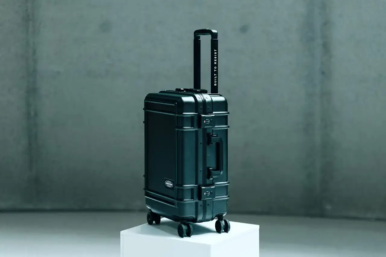 Eastpak Resist'r Case hard-shell luggage in three sizes - small, medium, and large - displayed in red, gray, and black colors. The suitcases feature a sleek polycarbonate exterior with aluminum frame, quiet wheels, and TSA-approved locks. Eastpak logo visible on the front color black
