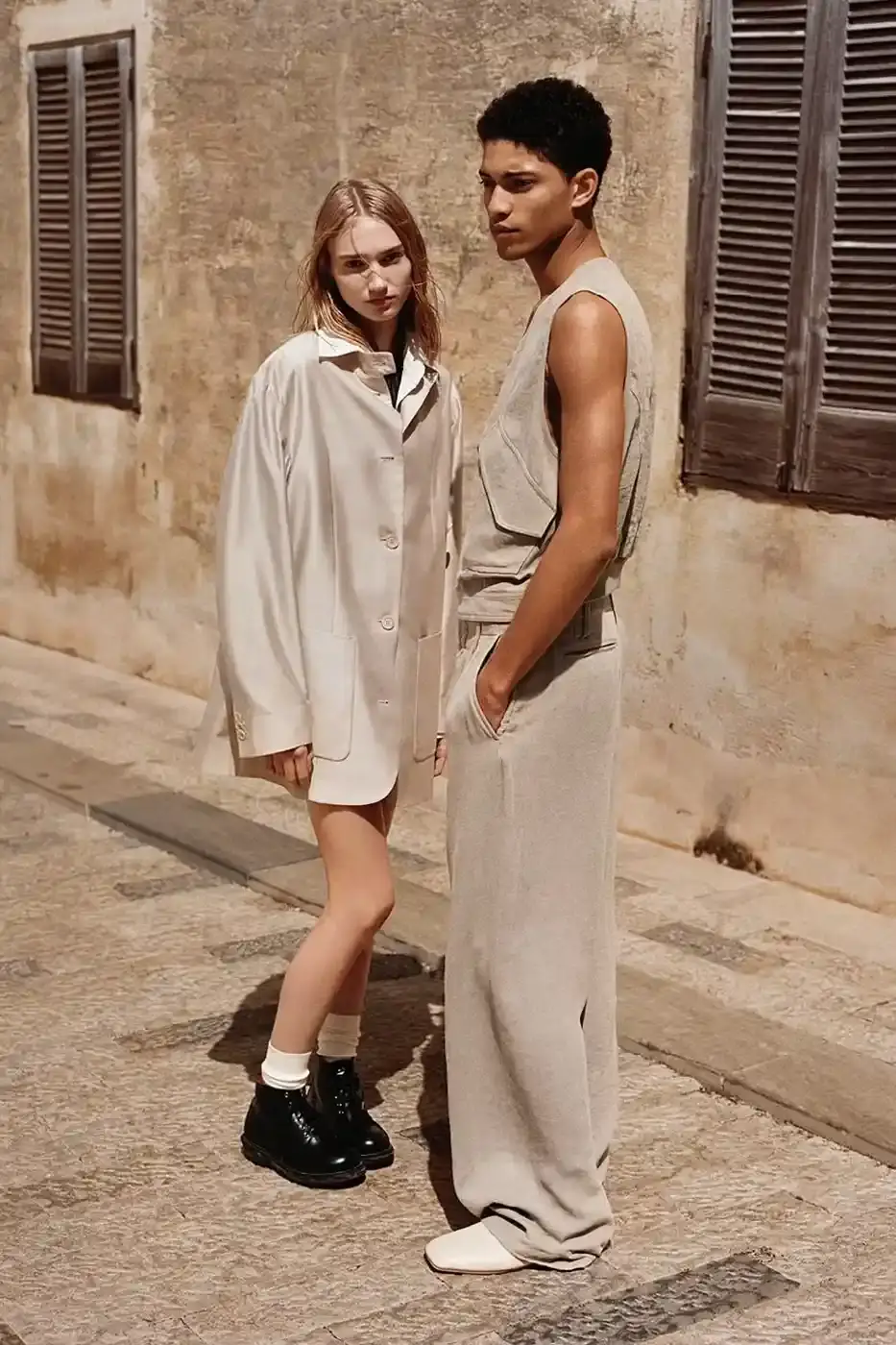 EMPORIO ARMANI AND OUR LEGACY: A SECOND CHAPTER IN DESIGN DIALOGUE image of second collaboration between Emporio Armani and Our Legacy Work Shop, detailing the expanded capsule collection that includes both menswear and womenswear. The collection features designs reimagined from Armani archives with East Asian influences, using both classic and recreated vintage fabrics. The article describes the campaign photographed by Alasdair McLellan on Pantelleria island, and provides information about the May 16 launch date and various retail locations where the collection will be available. (image 6 of 7)