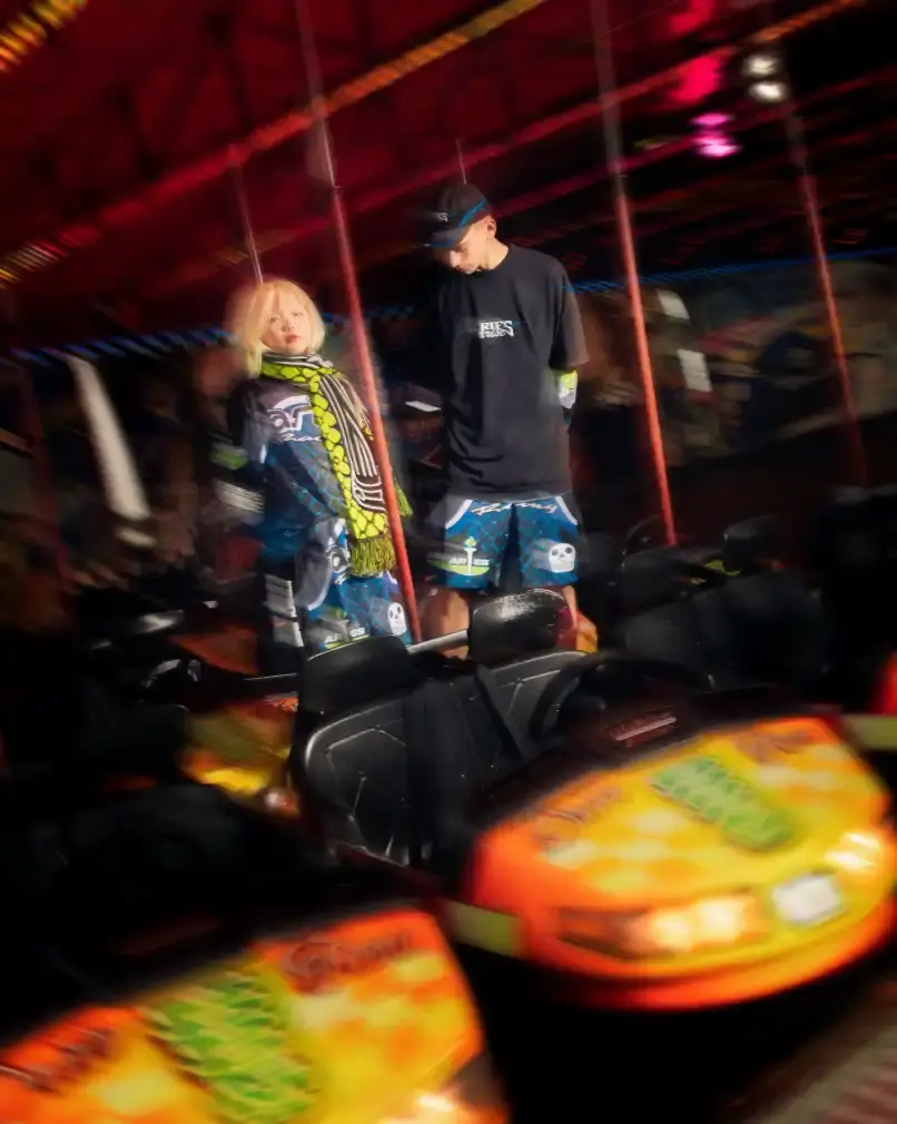 END. AND ARIES LAUNCH ARCADE-INSPIRED COLLECTION image of the launch of a collaborative fashion collection between retailer END. and streetwear brand Aries. The nine-piece "Arcade" collection draws inspiration from 1990s arcade games and motorsports culture, featuring items like graphic t-shirts, shorts, accessories, and caps with racing-themed designs. The piece includes details about pricing (£35-£170), availability through END.'s online store and physical locations, and the campaign photography shot in an actual arcade setting. The collaboration marks part of END.'s 20th anniversary and represents Aries' first partnership with the retailer. (image 6 of 9)